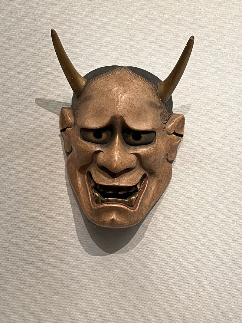 Nohmasker van een demon met hoorns en een grijns